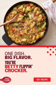 a pan filled with food sitting on top of a table next to a wooden spoon