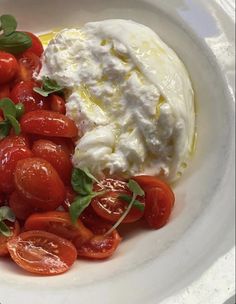 a white plate topped with tomatoes and whipped cream