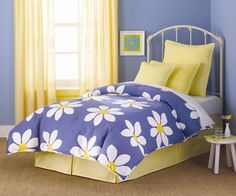 a blue and yellow bed with white daisies on the comforter in a bedroom