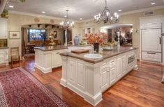 a large kitchen with wooden floors and white cabinets on the walls, along with a center island