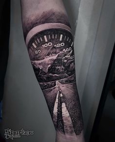 a man's arm with a clock on the road and mountains in the background