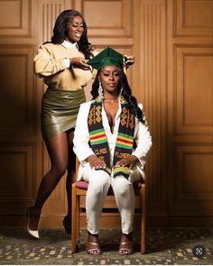 two women sitting in chairs and one is wearing a graduation cap