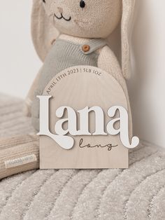 a stuffed animal sitting on top of a bed next to a sign that says lamaa long