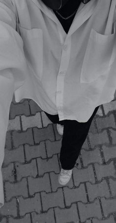 a person wearing a white shirt and black pants is standing on a brick walkway with their hands in the air