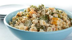 a blue bowl filled with food on top of a white table next to a plate