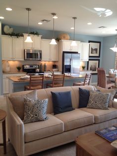 a living room filled with furniture next to a kitchen and dining room table in the background