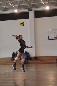 a woman jumping up in the air to catch a yellow ball with her right hand