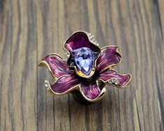 a purple flower ring sitting on top of a wooden table