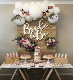 a table topped with cake and balloons next to a wooden sign that says bridal