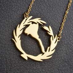 a gold plated necklace with an image of a bird in a wreath on it