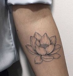 a black and white lotus flower tattoo on the right arm, with an arrow in the center