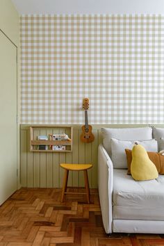 a living room with a couch, guitar and bookshelf on the wall behind it