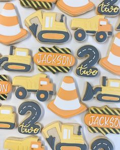 decorated cookies with construction vehicles are displayed on a white tablecloth for the first birthday boy