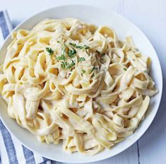 a white bowl filled with pasta and sauce on top of a blue and white towel