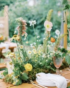 the table is set with flowers and place settings for an outdoor dinner or reception party