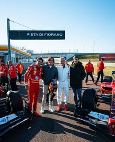 some people are posing for a photo in front of their race cars at the pit