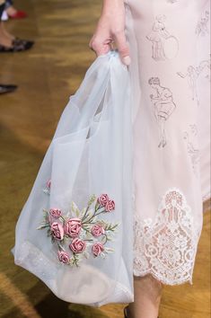 a close up of a person holding bags with flowers on them and wearing high heels