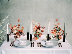 the table is set with candles and flowers in vases on top of each plate