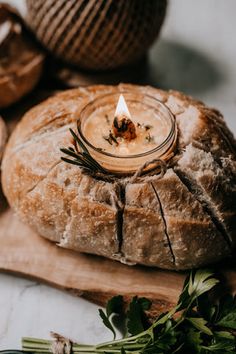 a candle sitting on top of a wooden cutting board next to bread and other items