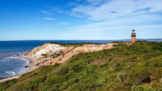 a light house sitting on top of a hill next to the ocean