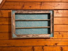 an old window in the side of a wooden building with blue wallpaper and wood paneling