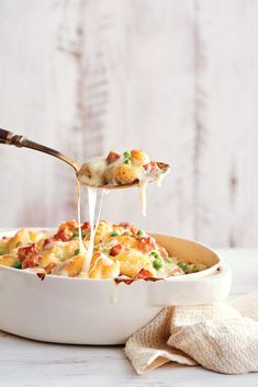 a spoon full of macaroni and cheese being lifted from a casserole dish