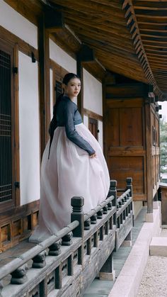 a woman in a long white dress standing on a porch