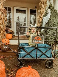 a baby sitting in the back of a truck with pumpkins on it's side