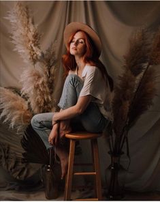 a woman with red hair sitting on a stool in front of some pamodils