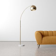 a yellow couch sitting next to a lamp on top of a white floor in front of a wall