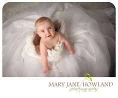 a baby in a white dress laying down