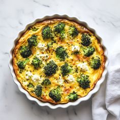 broccoli and cheese casserole in a white dish on a marble surface