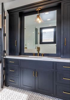 a large bathroom with black cabinets and gold pulls on the doors, along with a marble countertop