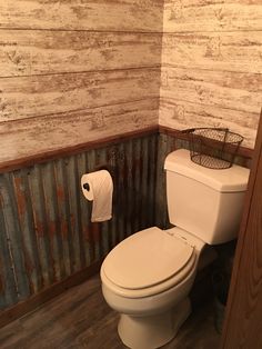 a white toilet sitting in a bathroom next to a wooden wall