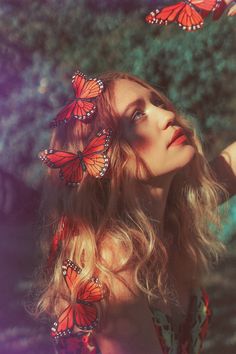 a woman with long blonde hair and butterfly wings on her head is looking up at the sky