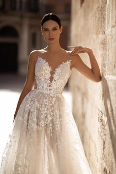 a woman in a wedding dress leaning against a wall