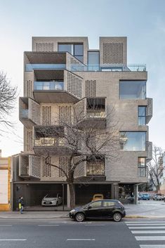 a car parked in front of a tall building with balconies on the sides