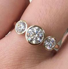 a woman's hand with three diamond rings on it and one is wearing a gold band