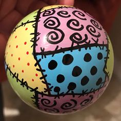 a hand holding a painted ball with designs on it