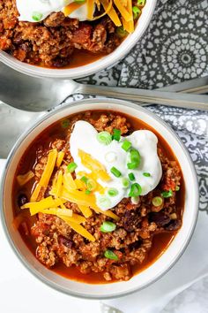 two bowls filled with chili and sour cream