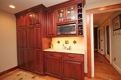 a kitchen with wooden cabinets and marble counter tops, along with an area rug on the floor