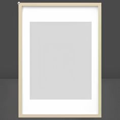 a white frame hanging on the wall with a black floor and grey walls behind it