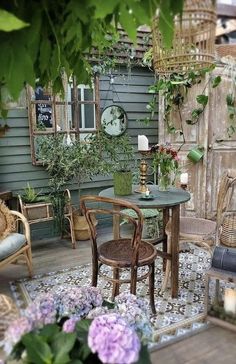 an outdoor patio with wicker furniture and flowers on the table, surrounded by greenery