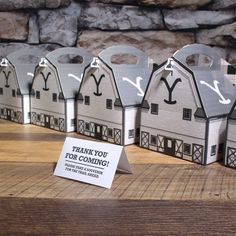 small paper houses are lined up on a table with a thank you for coming sign