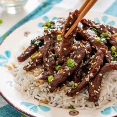 beef and rice with chopsticks on a blue and white table cloth, ready to be eaten