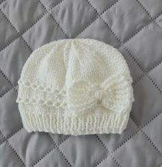 a white knitted hat laying on top of a bed