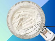 whipped cream in a bowl with whisk attachments on a blue and green background