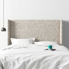 a bed with white sheets and pillows in a bedroom next to a wall mounted light