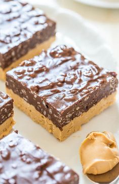 three pieces of chocolate peanut butter bars on a white plate with a spoon next to it