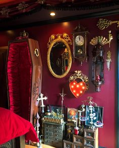 a room with red walls and lots of decorations on the wall, including an old dresser